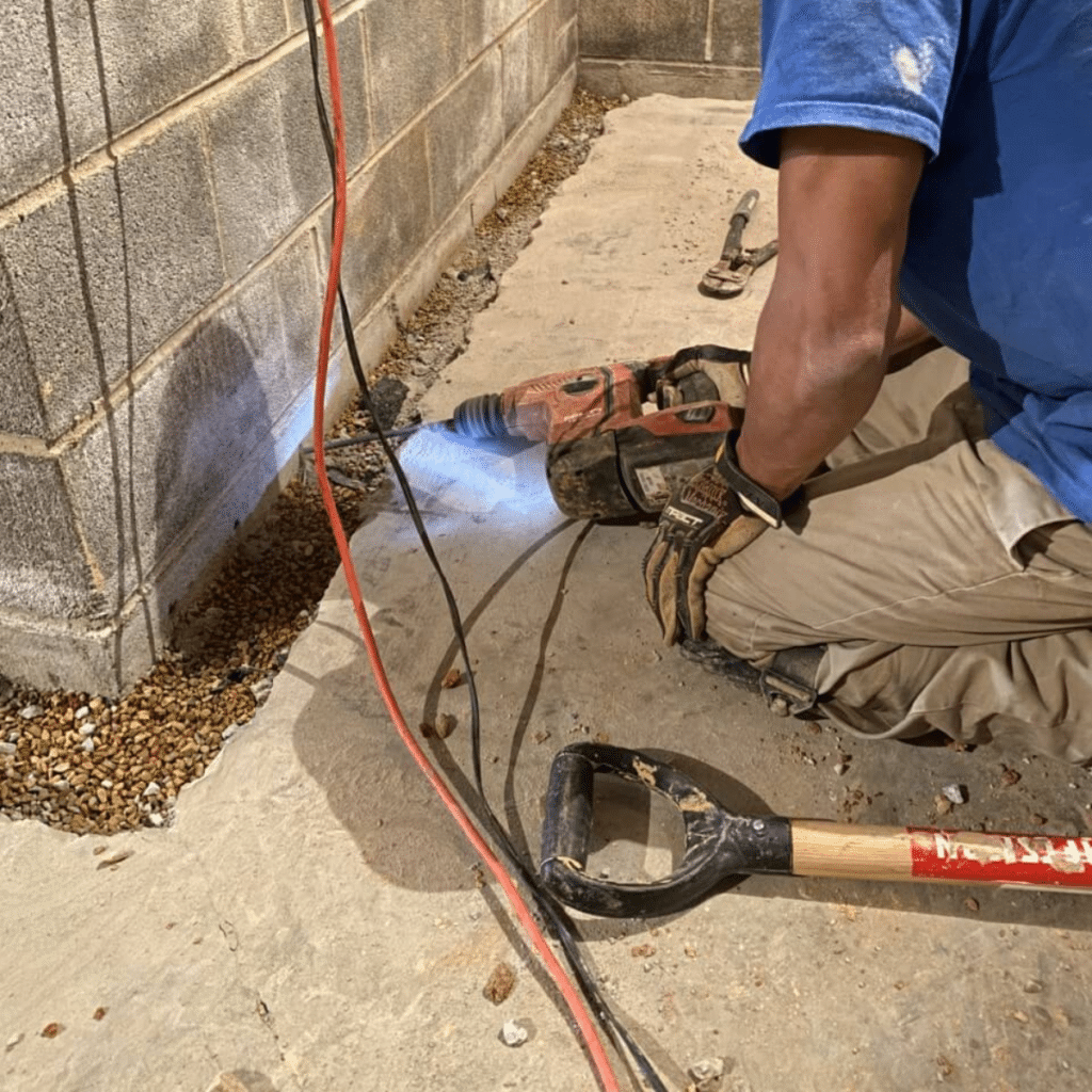 foundation repair worker drilling hole on a building's foundation