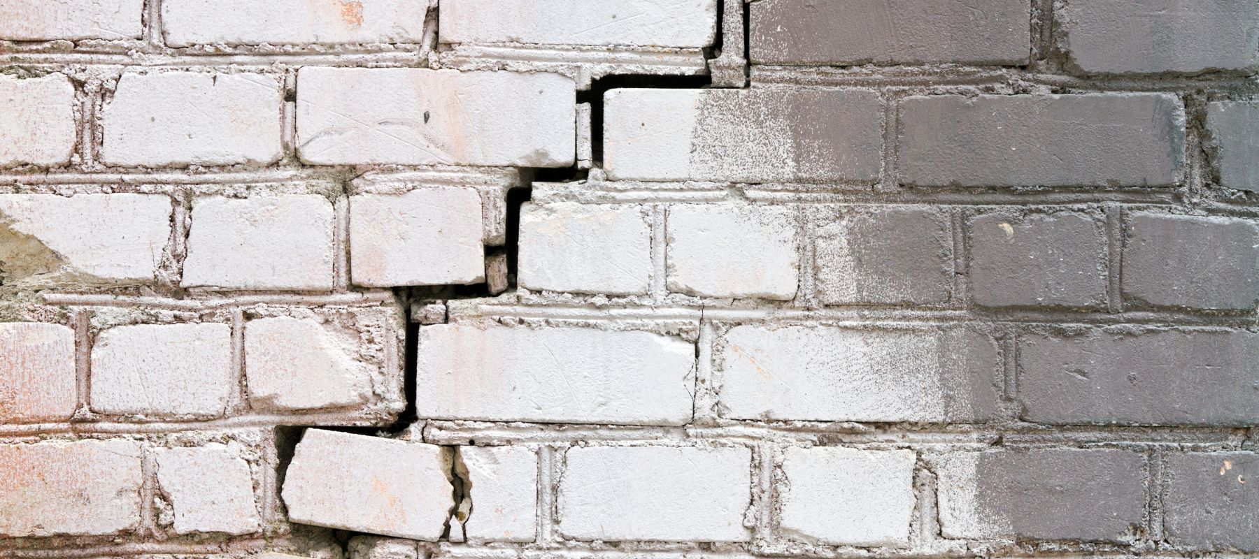 closeup of a white brick wall with a large crack running through it