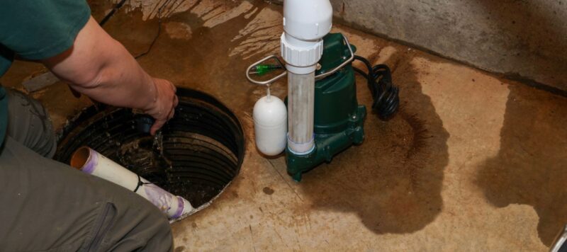 A plumber repairing a sump pump in a flooded basement in a residential home