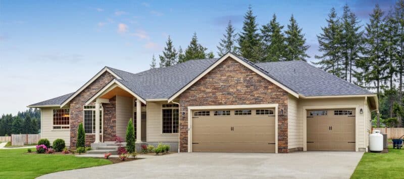 Single-story house with stone accents, tan siding, and a three-car garage